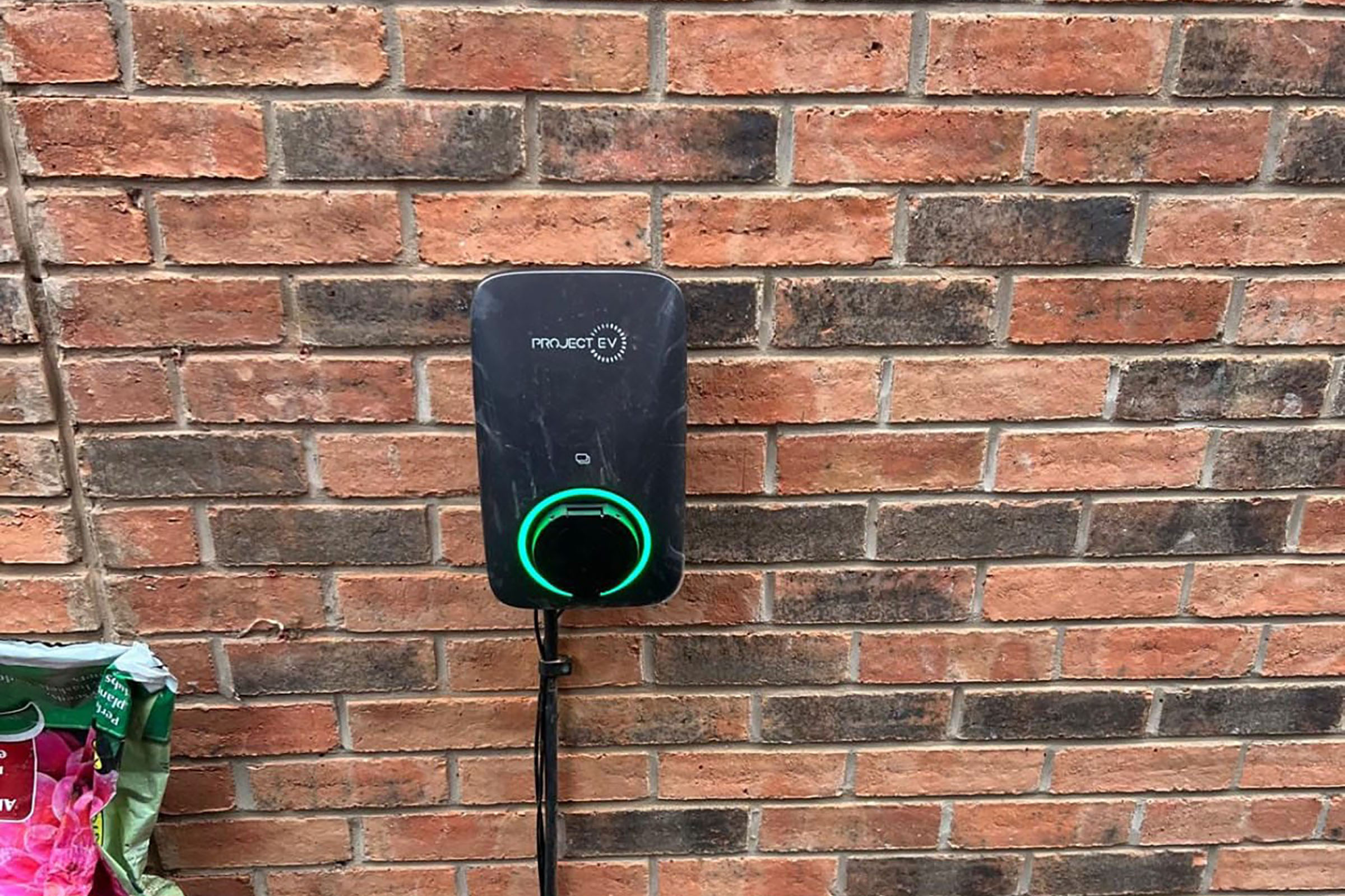 Electric vehicle charger mounted on brick wall