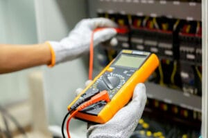 Electrician using multimeter on control panel