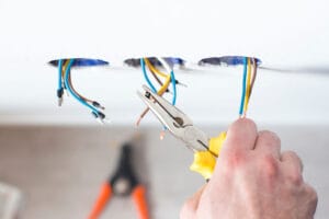 Electrician using pliers on ceiling wires