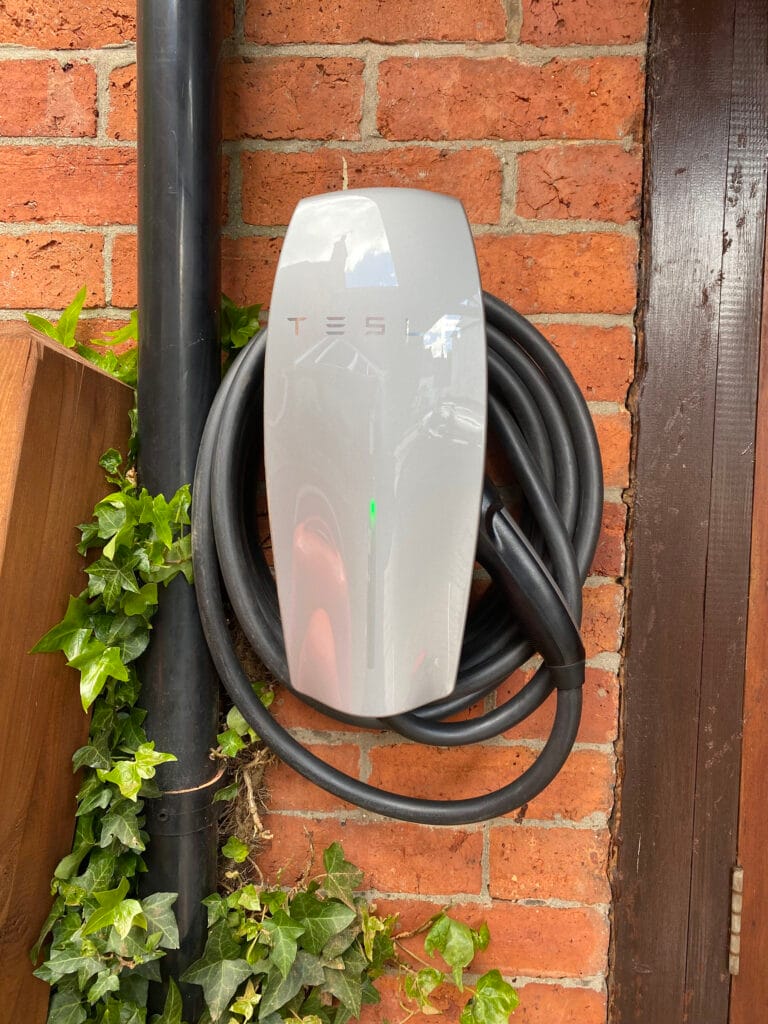 Wall-mounted electric vehicle charger with cable coiled.