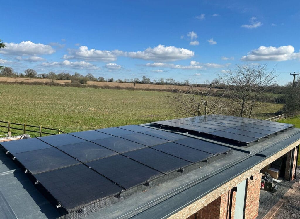 Rooftop solar panels on rural building under clear sky.