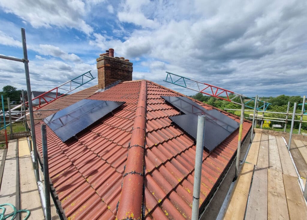 Solar panels on red tiled roof with scaffolding.