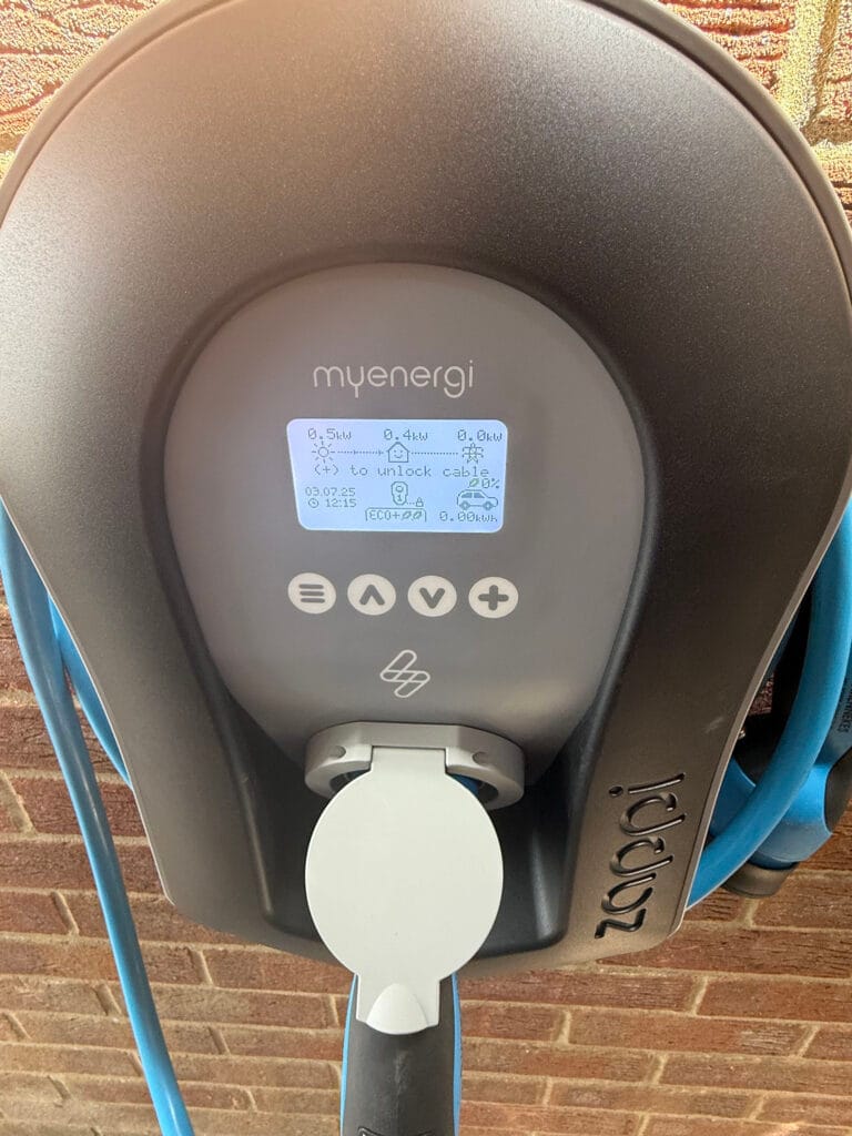 MyEnergi electric vehicle charger attached to brick wall.