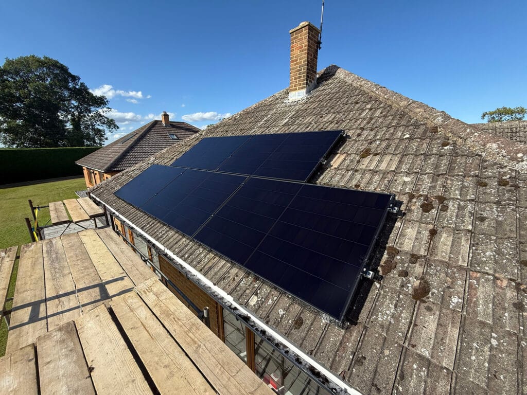 Solar panels installed on house roof under blue sky.