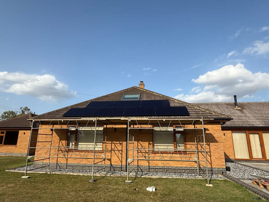 Bungalow with solar panels and scaffolding installed.