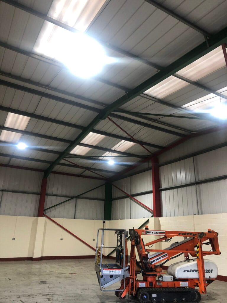 Warehouse interior with cherry picker and bright lighting.
