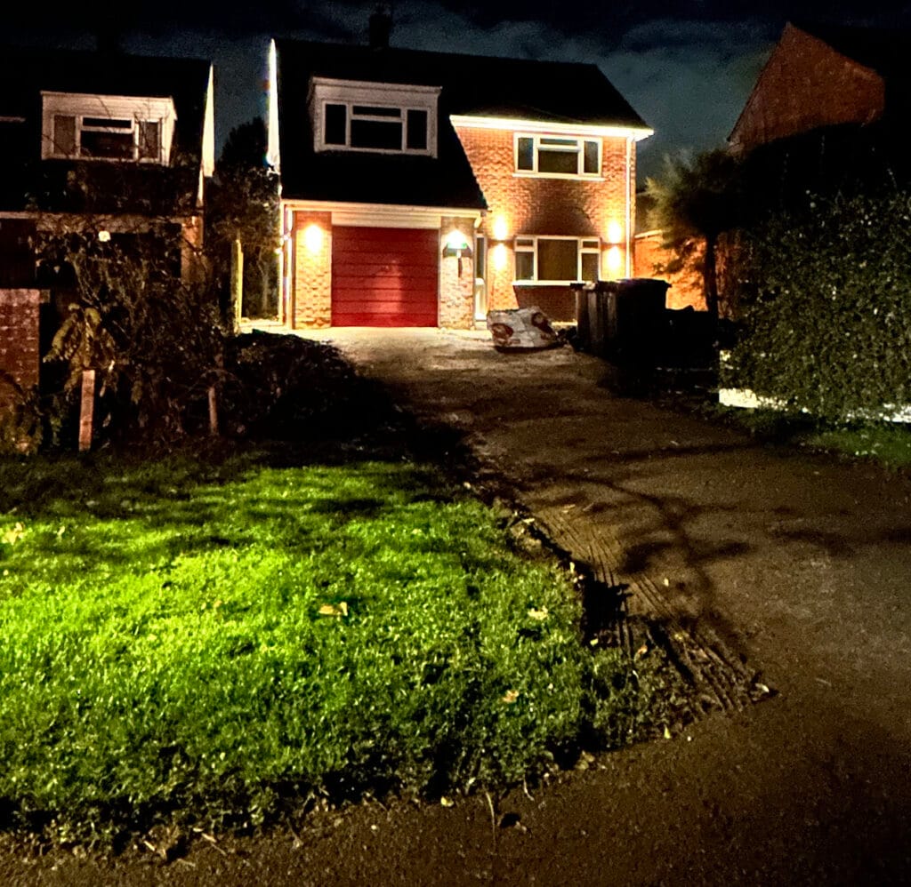 Illuminated house with red garage door at night.