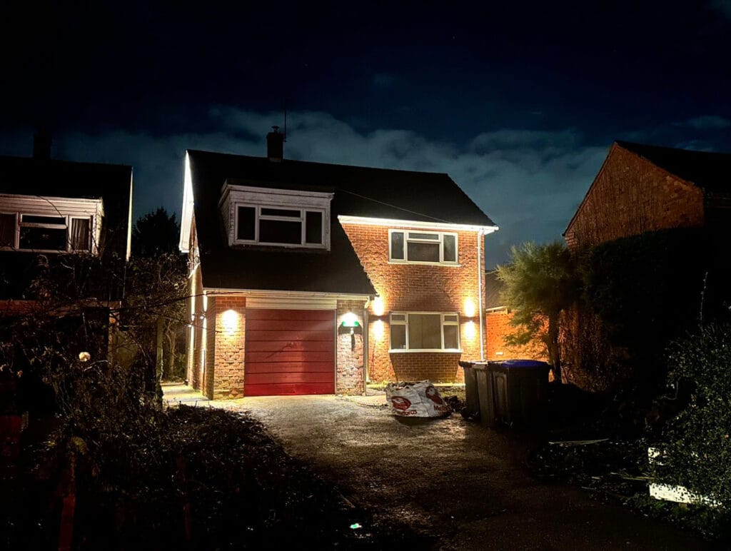 Illuminated brick house at night with driveway.